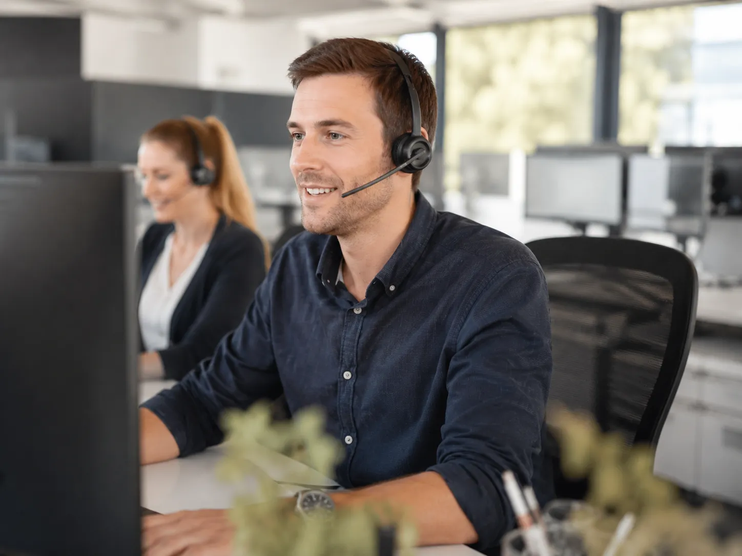 Innendienst-Mitarbeiter mit Headset am Arbeitsplatz